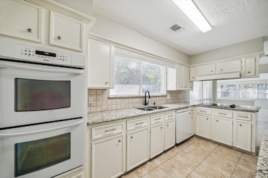 The kitchen overlooks the backyard and features tile floor, recent double ovens, 2024 dishwasher, and granite counter tops.