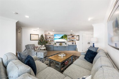 Living room featuring crown molding, built in features, and hardwood / wood-style flooring