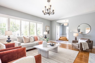 Living room featuring healthy amount of natural light, light wood finished floors, arched walkways, and stairway