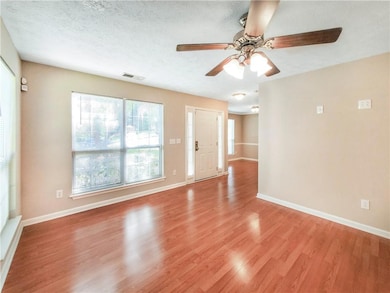 Unfurnished room featuring ceiling fan, light wood-style floors, baseboards, and a textured ceiling