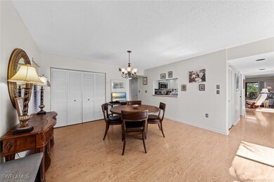 Dining area with light wood-style floors, a chandelier, a textured ceiling, and baseboards