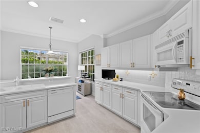 Kitchen with white cabinetry, sink, pendant lighti