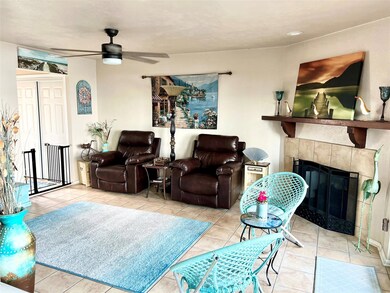 Tiled living room with a fireplace and ceiling fan