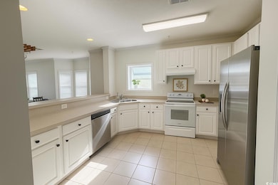 Kitchen with stainless steel appliances, white cabinetry, light tile patterned floors, crown molding, and recessed lighting