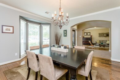 The formal dining room features beautiful wood floors, large bay windows, custom paint and a magnificent chandelier.