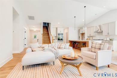 Living room with light wood-style floors, stairway, recessed lighting, and vaulted ceiling