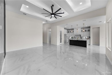 Unfurnished living room featuring a raised ceiling, recessed lighting, light marble finish flooring, and ceiling fan