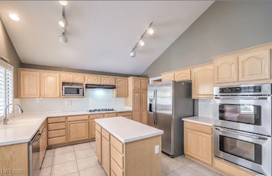 Kitchen featuring light brown cabinetry, lofted ce