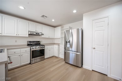 Kitchen featuring white cabinets, stainless steel appliances, light countertops, and recessed lighting