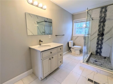 Full bathroom with a marble finish shower, vanity, crown molding, and marble finish flooring