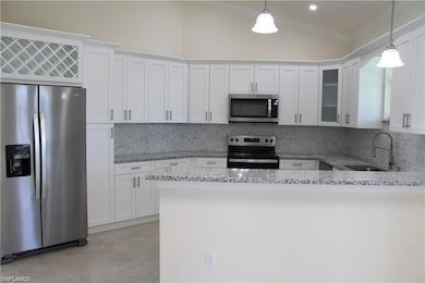 Kitchen featuring stainless steel appliances, a sink, crown molding, white cabinetry, and light stone countertops