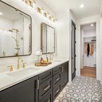 Bathroom featuring recessed lighting, a shower stall, double vanity, and a spacious closet
