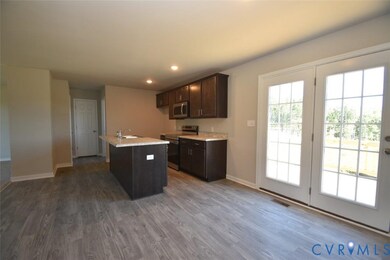 Kitchen with dark brown cabinets, stainless steel appliances, dark wood-style floors, a center island with sink, and recessed lighting