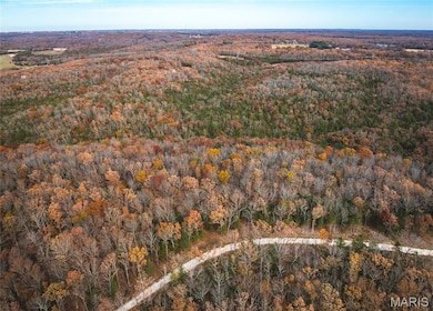 Aerial view of property and surrounding area featuring a forest
