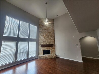 Unfurnished living room with ceiling fan, a stone fireplace, and dark hardwood / wood-style flooring