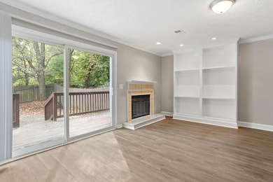 Unfurnished living room featuring wood finished floors, a tiled fireplace, ornamental molding, a textured ceiling, and recessed lighting
