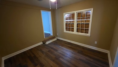 Empty room with dark wood finished floors and ceiling fan