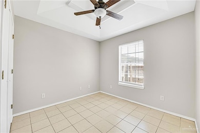Empty room with a ceiling fan, baseboards, and light tile patterned floors