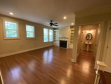 Unfurnished living room with crown molding, a ceiling fan, wood finished floors, a fireplace with flush hearth, and recessed lighting