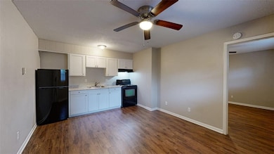 Kitchen with black appliances, light countertops, dark wood-style floors, white cabinets, and ceiling fan