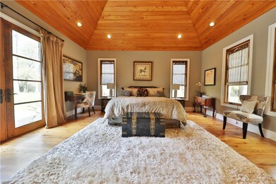 Large master bedroom suite with stained tongue and groove wooden paneling on vaulted ceiling; lots of natural light