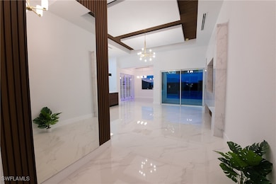 Hall featuring a raised ceiling and a chandelier