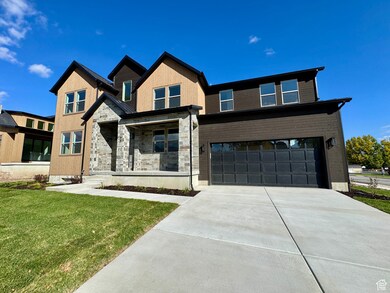View of front of house with covered porch, an attached garage, a front lawn, driveway, and stone siding