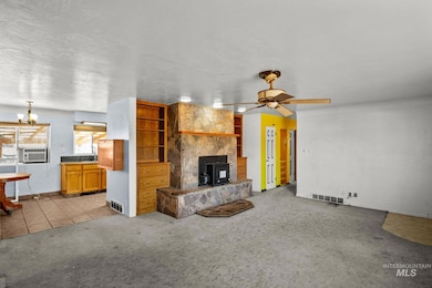 Unfurnished living room featuring a wood stove, light carpet, light tile patterned floors, ceiling fan, and a textured ceiling