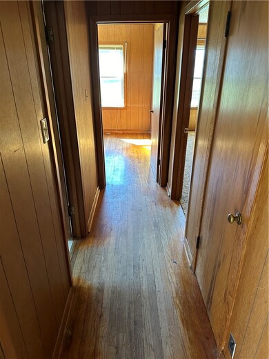 Corridor featuring light wood-type flooring and wooden walls