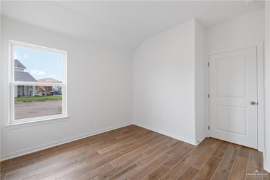 Additional living space with wood finished floors, lofted ceiling, and baseboards