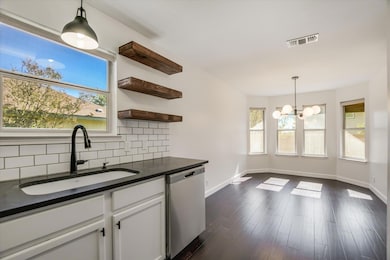 Kitchen featuring pendant lighting, stainless steel dishwasher, plenty of natural light, and tasteful backsplash