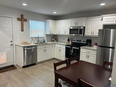 Kitchen with appliances with stainless steel finishes, white cabinetry, light stone counters, light wood-style flooring, and recessed lighting
