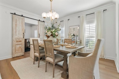 Dining area featuring a barn door, ornamental molding, wood finished floors, healthy amount of natural light, and a chandelier