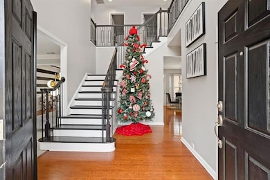 Foyer with light wood-type flooring, stairs, and a high ceiling