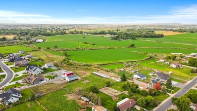 Aerial view of property and surrounding area featuring rural landscape, mountains, and nearby suburban area