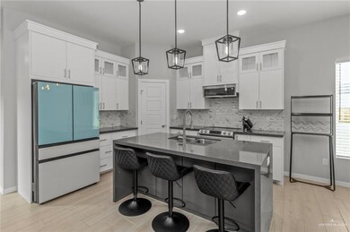 Kitchen with a center island with sink, stainless steel appliances, tasteful backsplash, sink, and pendant lighting
