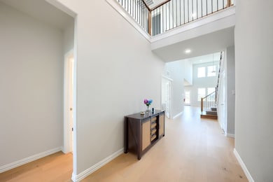 Hall with a high ceiling, light wood-style flooring, stairs, and recessed lighting