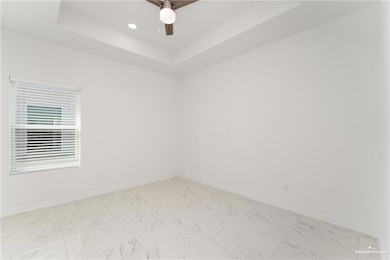 Spare room featuring baseboards, ceiling fan, a tray ceiling, recessed lighting, and marble finish floor