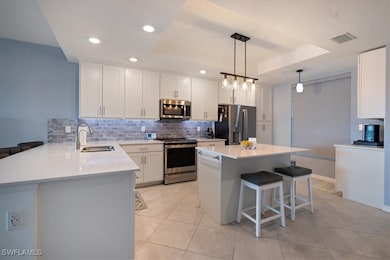 Kitchen featuring a raised ceiling, white cabinetr
