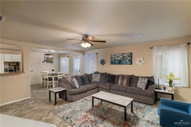 Living area featuring arched walkways, a ceiling fan, and a chandelier