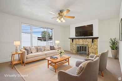 Living area with carpet floors, a fireplace, and ceiling fan