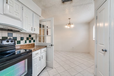 Kitchen with black range with electric stovetop, white cabinets, light tile patterned flooring, a textured ceiling, and tasteful backsplash
