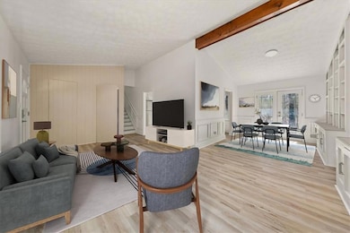 Living area featuring stairs, light wood-style flooring, and a decorative wall