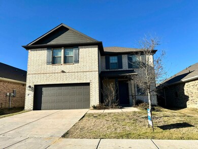 Traditional home with a garage, brick siding, and driveway