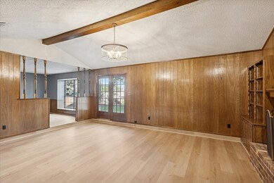 Living room with wood walls, light wood finished floors, a chandelier, and a textured ceiling
