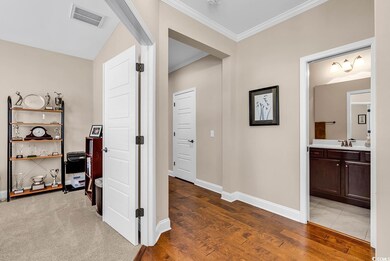 Hall with visible vents, wood finished floors, crown molding, and a sink