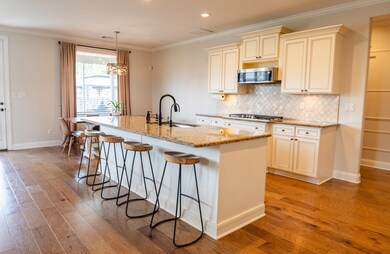 Kitchen featuring a sink, stainless steel appliances, light wood finished floors, an island with sink, and a kitchen breakfast bar