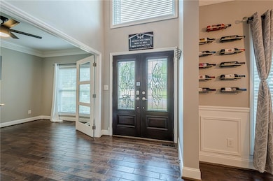 Foyer with healthy amount of natural light, ornamental molding, dark wood-style floors, french doors, and a ceiling fan