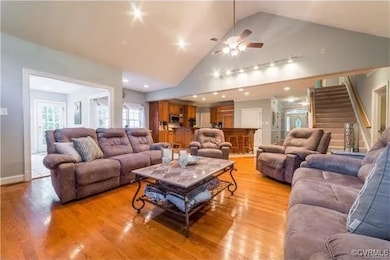 Living room featuring a ceiling fan, high vaulted