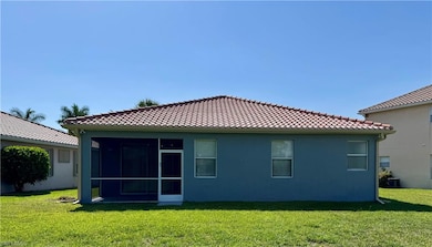 Back of house with a lawn, a tile roof, and stucco siding